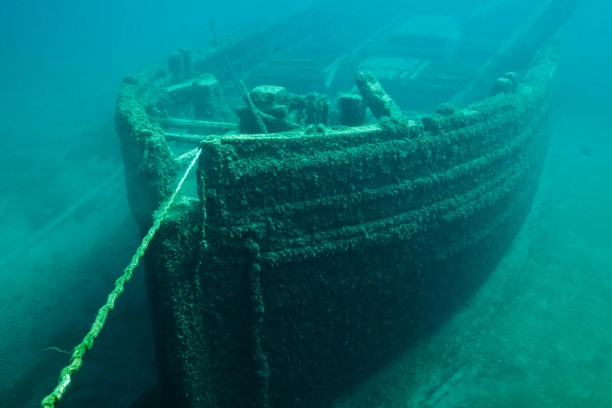 A sunken wooden shipwreck rests in clear blue-green water